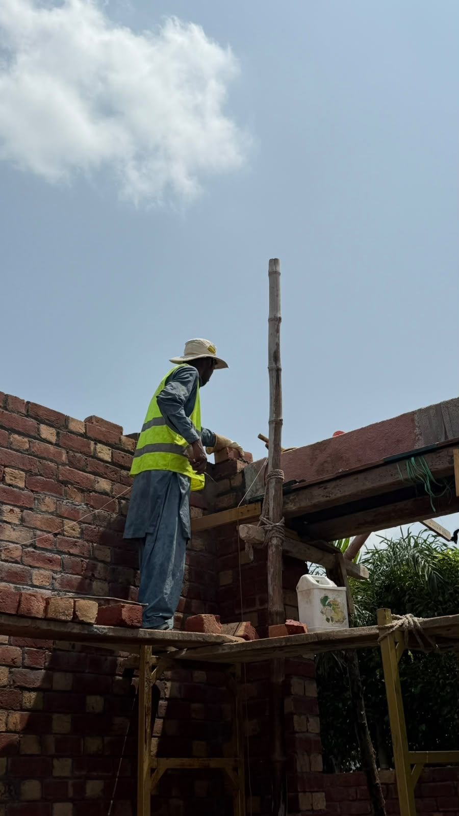 Construction worker in safety vest building a brick wall on a house site in Lahore