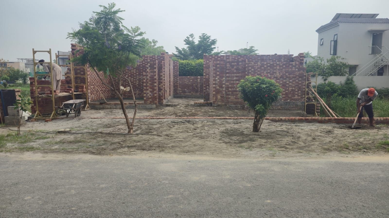 Brick masonry wall rising on a plot at the start of house construction in Lahore