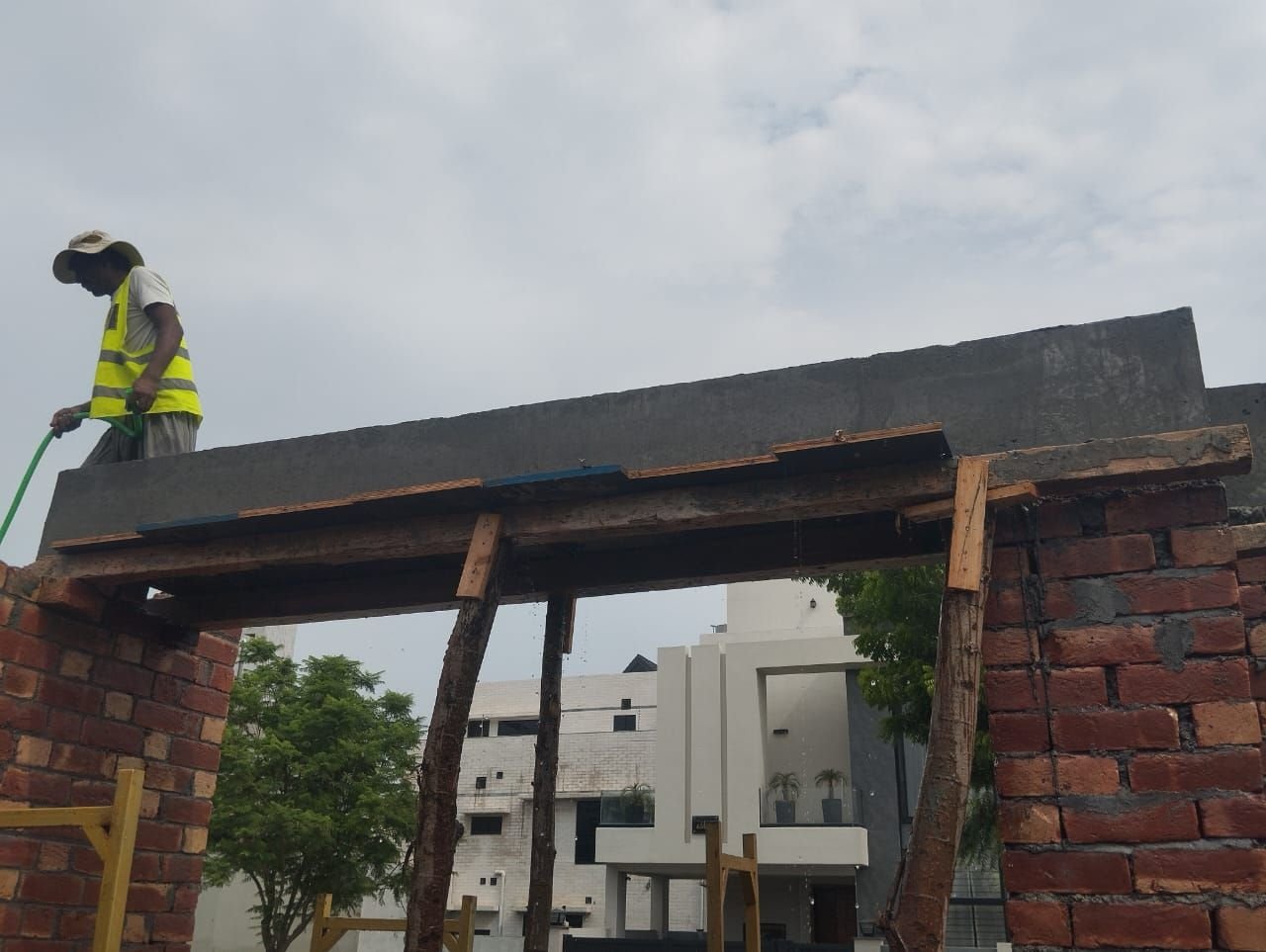 Worker on lintel shuttering above a brick opening during house construction in Lahore