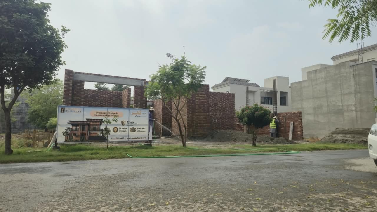 Glorious Builders site board in front of a house under construction in Lahore