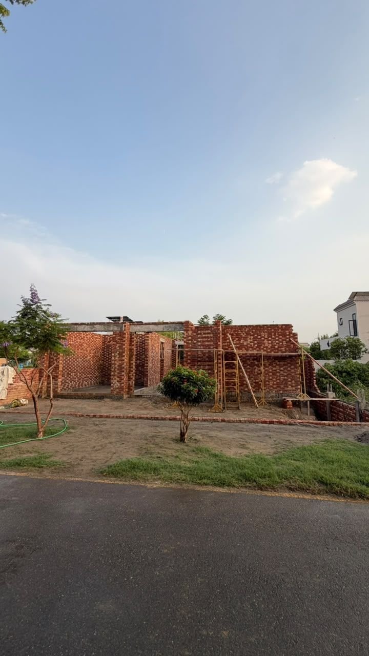 Distant view of a brick house structure under construction on a Lahore street
