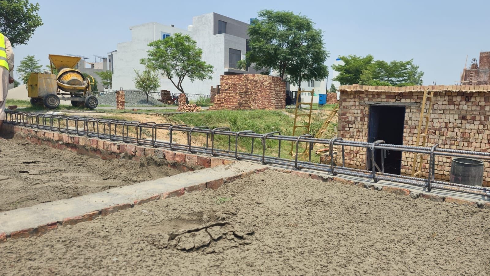 Compacted plinth filling with steel bars and concrete mixer on a residential construction site in Lahore