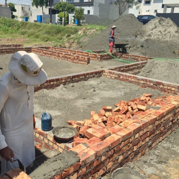Mason laying bricks for foundation walls on a house plot in Lake City Lahore