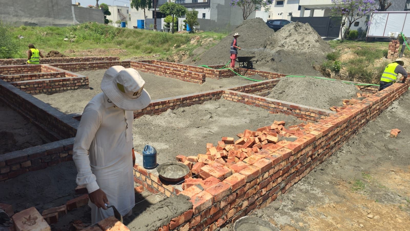 Mason laying bricks for foundation walls on a house plot in Lake City Lahore
