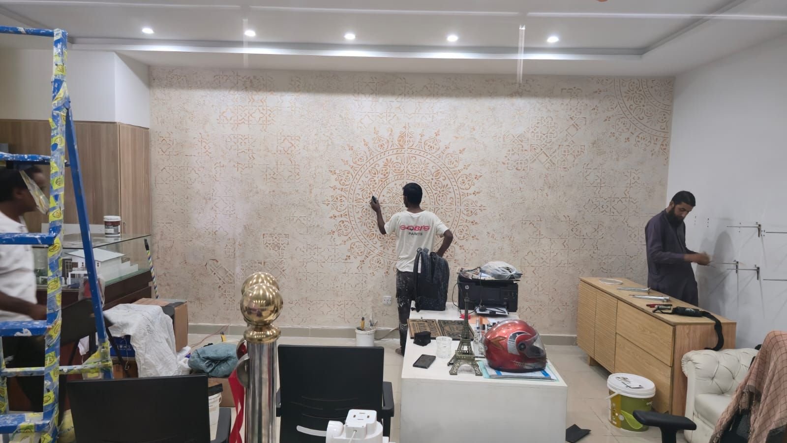 Workers finishing an interior wall surface inside a room of a house in Lake City Lahore