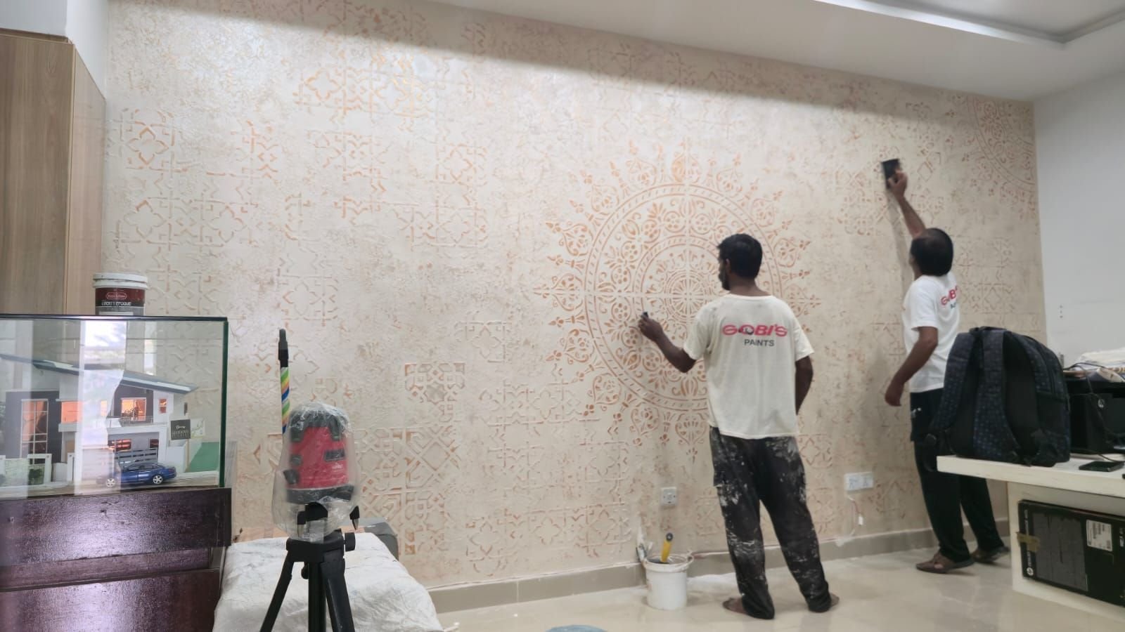 Workers applying a textured finish on an interior wall at a house in Lake City Lahore