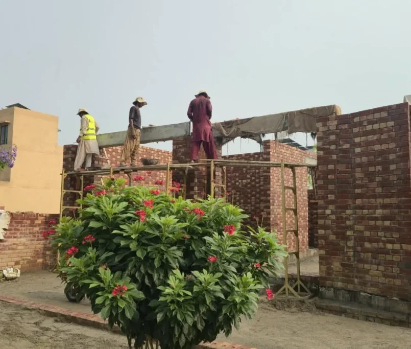 Masons and roof slab shuttering at lintel level on a house under construction in Lahore