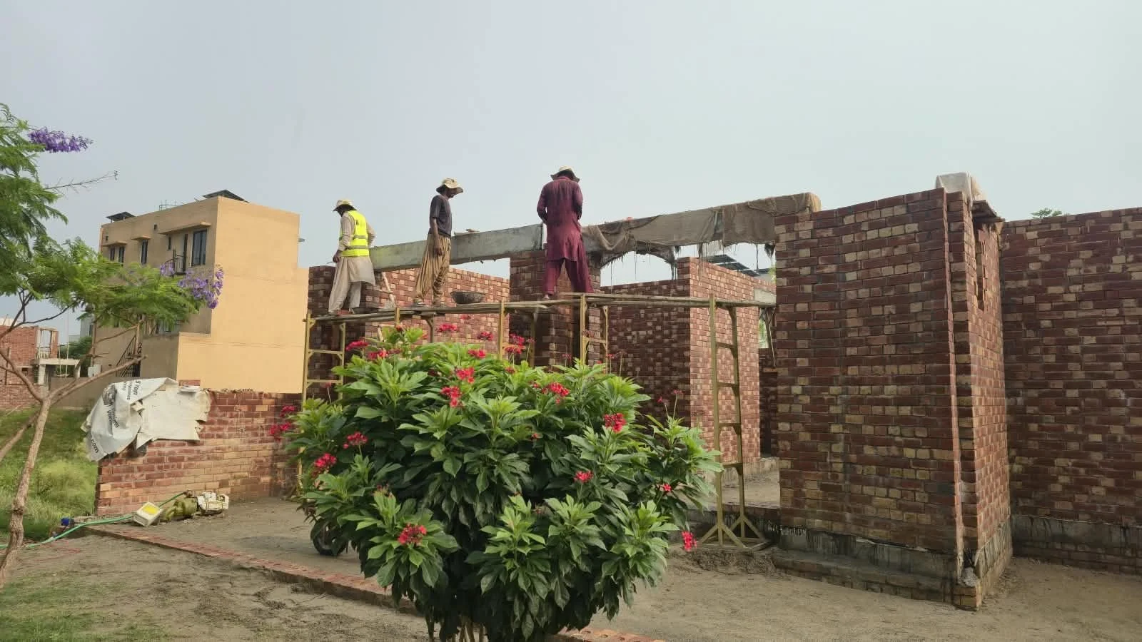 Masons and roof slab shuttering at lintel level on a house under construction in Lahore